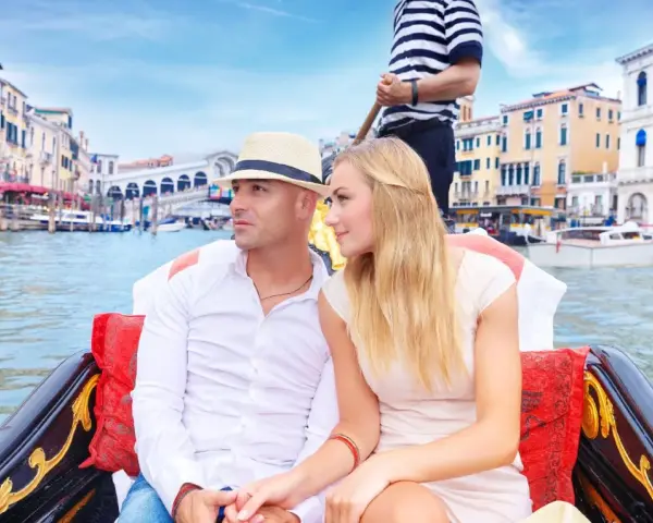 Coppia romantica su gondole a Venezia, con edifici storici sullo sfondo.