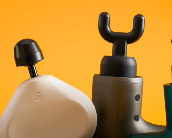 Four percussion massagers with different attachments are lined up against a bright orange background.
