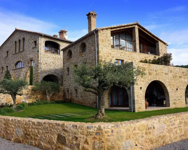 Magnifique maison en pierre calcaire avec des arches et un jardin verdoyant.