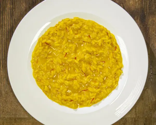 Un cremoso risotto alla milanese, con i suoi fili rossi di zafferano che promettono un sapore autentico.