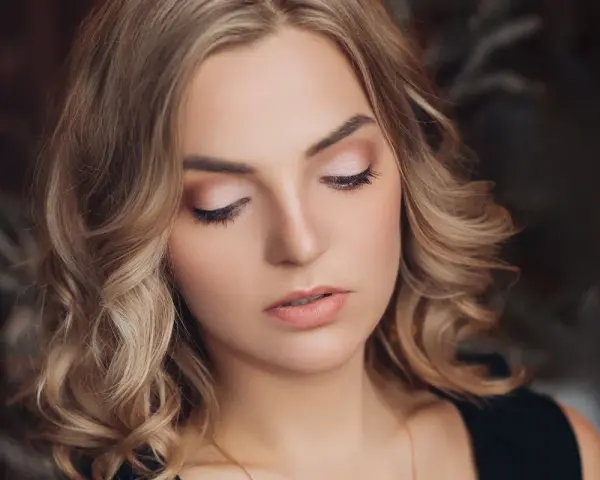 Delikatny makijaż na święta podkreśla urodę kobiety z blond włosami.
