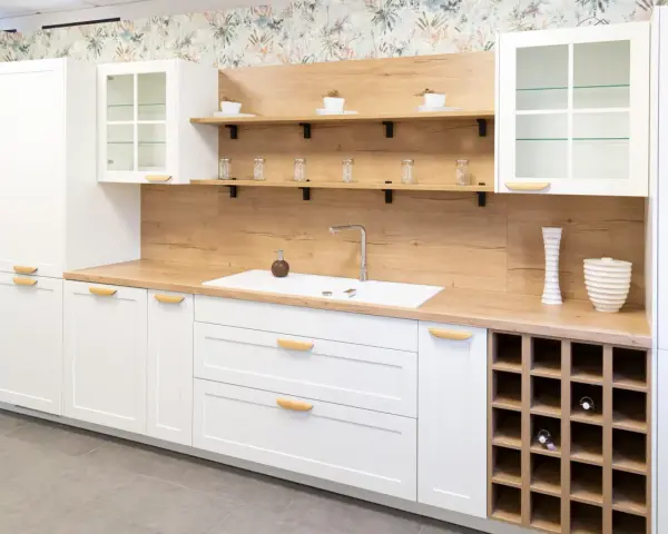 Cocina moderna blanca con encimera de madera, estantes flotantes y botellero. Inspiración para tus ideas de cocinas.