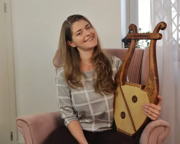 Uśmiechnięta kobieta trzyma instrument muzyczny, który wygląda jak skorupa żółwia.