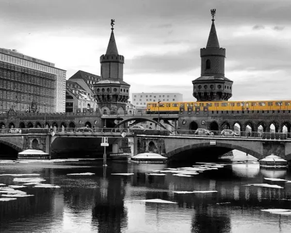 Gelbe U-Bahn fährt über die Oberbaumbrücke in Berlin. Eisschollen treiben auf dem Wasser.