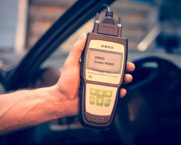 Hand holding an OBD2 scanner displaying code P0011, ready to diagnose car issues.