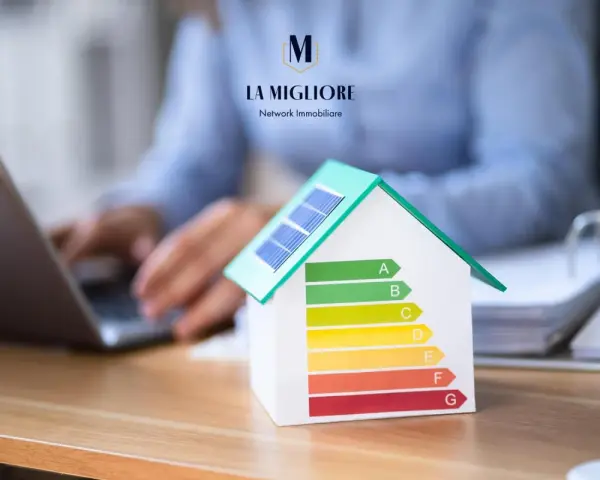 Modello di casa con pannelli solari e scala di efficienza energetica. La migliore immobiliare valuta la classe energetica casa.