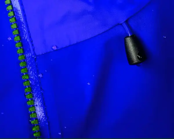 Nahaufnahme einer blauen Gore-Tex-Jacke mit Reißverschluss und Wassertropfen. So pflegt man Gore-Tex richtig beim Waschen.