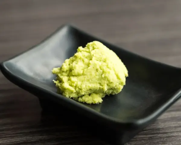Zielona pasta, czyli co to jest wasabi, na czarnej, kwadratowej miseczce.