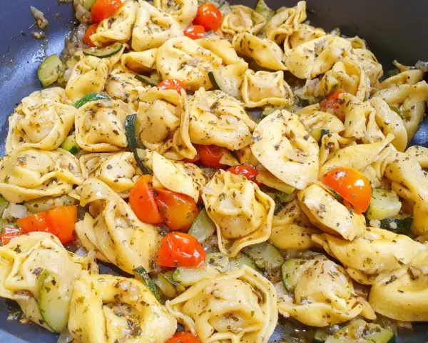 Pyszne danie z tortellini na obiad, z pomidorkami koktajlowymi i cukinią, doprawione ziołami.