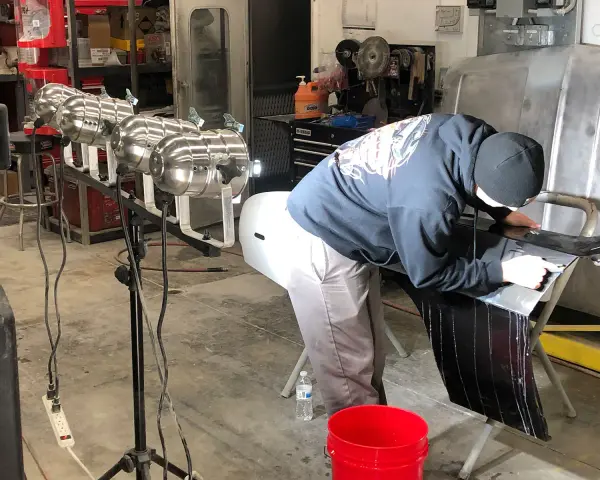 A person in a garage works on a car part, learning how to buff it to a shine.