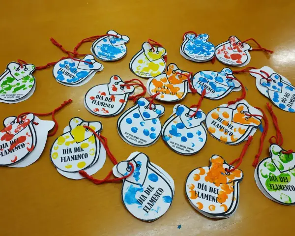 Manualidades flamencas para niños: castañuelas de papel con huellas dactilares de colores, decoradas para el Día del Flamenco.