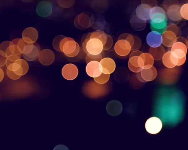 Rozmyte, okrągłe światła tworzą magiczny **bokeh** na ciemnym tle.