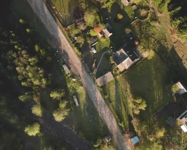 Widok z lotu ptaka na wiejską drogę i domy. Widać, jak pochyła działka wymaga wyrównania, by stworzyć płaski teren pod zabudowę.