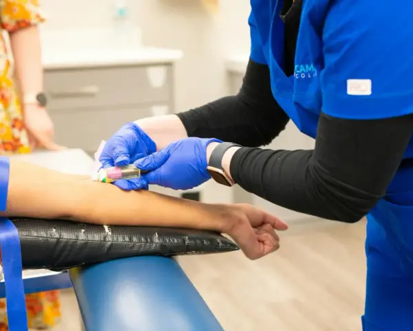 Pielęgniarka w niebieskim uniformie podczas kursu medycyny pracy pobiera krew.