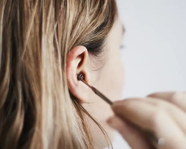 Une personne utilise un outil pour nettoyer son oreille. Les boules quies me font mal aux oreilles, alors je préfère cette méthode.