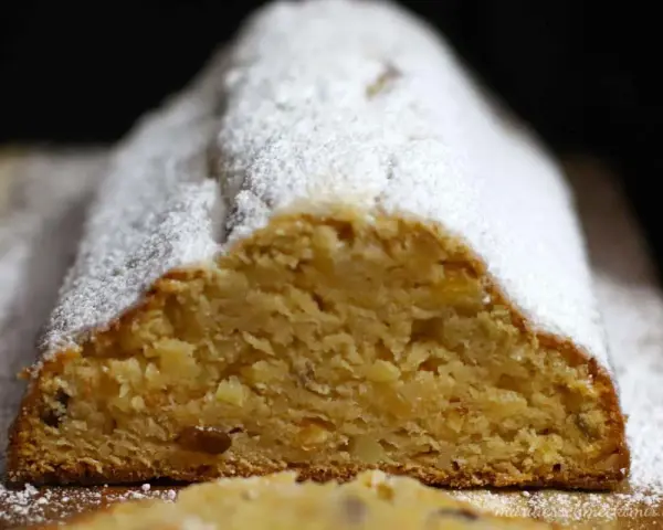 Ein saftiger Quarkstollen mit Marzipan, bestäubt mit Puderzucker, wartet auf den Anschnitt.