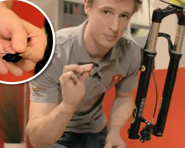 Man visar hur man byta bromsklossar på en cykel. En närbild visar en liten svart bromskloss.