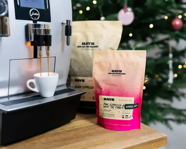 Espresso z ekspresu Jura, obok paczki kawy HAYB "Pink Espresso Barrel Aged". W tle choinka.