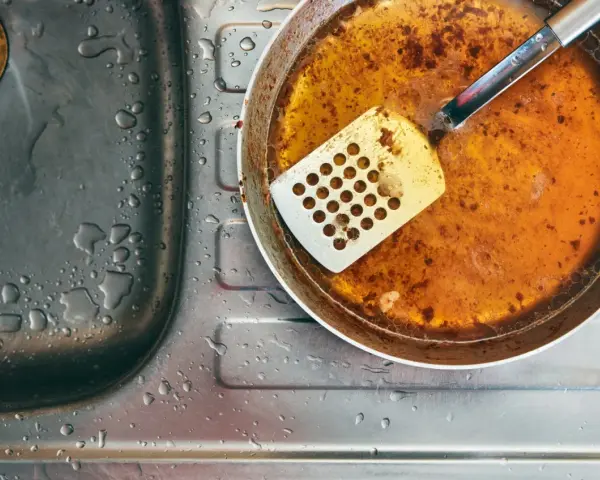Zlepek zużytego oleju gastronomicznego na patelni obok zlewu.
