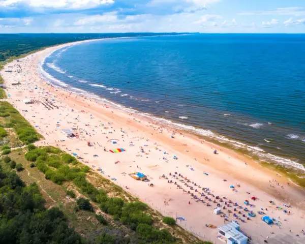 Szeroka, piaszczysta plaża z tłumem turystów, zielony las i błękitne morze – to jedne z najpiękniejszych plaż w Polsce.
