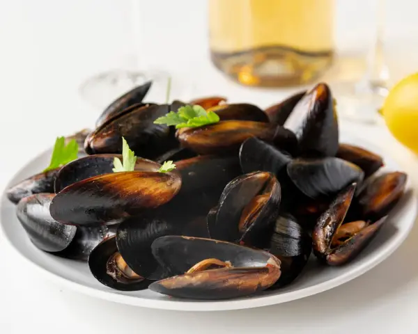 Plato de mejillones al vapor, listos para disfrutar con un toque de limón y perejil.