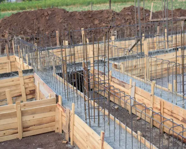 Drewniany szalunek fundamentowy z zbrojeniem stalowym, gotowy do wylania betonu.