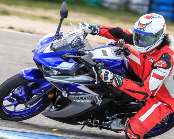 Motocyklista w czerwonym kombinezonie i kasku ściga się na torze na motocyklu Yamaha R3.