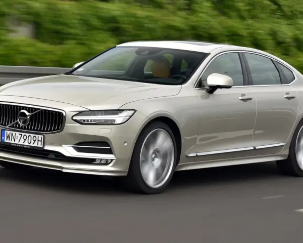 Eleganckie Volvo S90 w kolorze szampańskim pędzi po drodze. Choć piękny, warto pamiętać o potencjalnych wadach tego modelu.