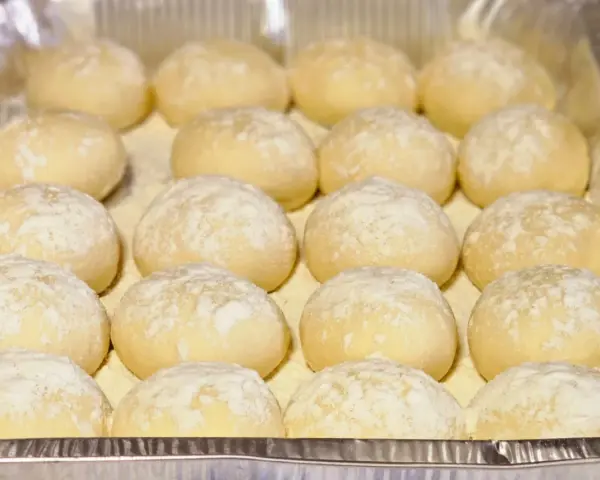 Piccolo pane fatto in casa, soffice e leggermente infarinato, pronto per essere infornato.