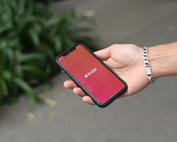 Dłoń trzyma smartfon z otwartą aplikacją Tinder. Zastanawiasz się, jak znaleźć osobę z Tindera na Facebooku?
