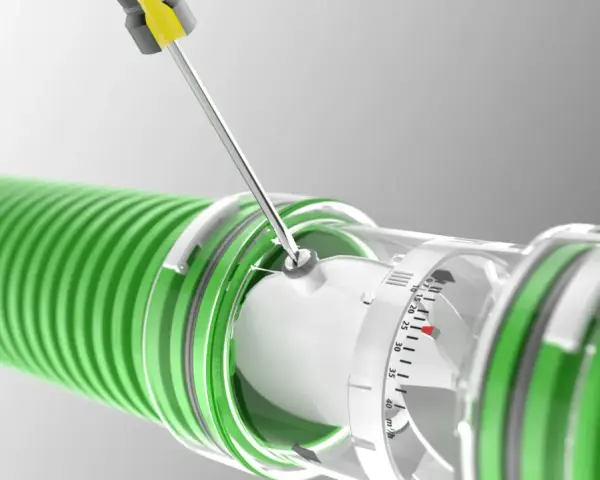 A screwdriver adjusts a clear dial on a green hose, indicating the regulador caudal.