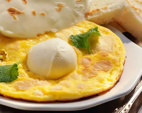 Frittata soffice con mozzarella filante, guarnita con foglie di menta fresca. Accompagnata da fette di pane tostato.