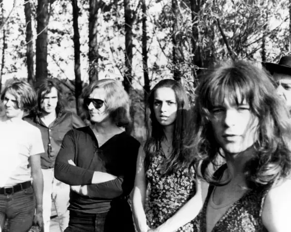 Un groupe rock allemand des années 70, avec des membres aux cheveux longs et des tenues décontractées, posant devant des arbres.