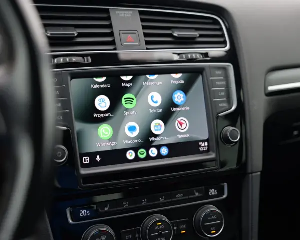 Ekran samochodu z widoczną aplikacją Android Auto, wyświetlającą ikony Kalendarz, Mapy, Spotify, WhatsApp i inne.