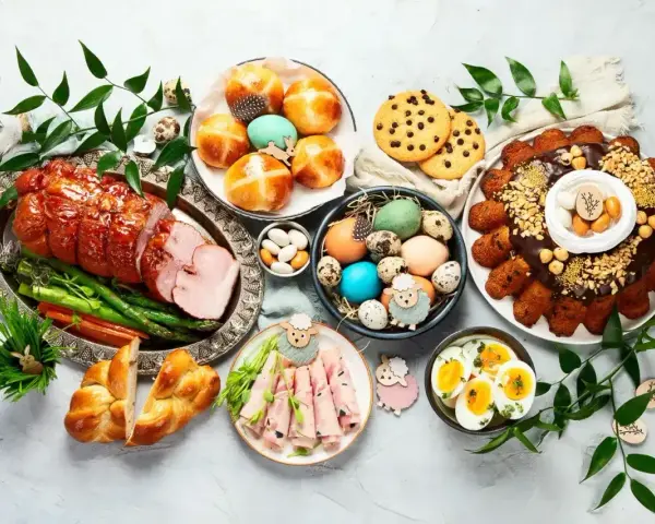 Wielkanocny stół pełen pyszności: pieczony schab, babka, pasztety, jajka, bułeczki i inne przekąski na wielkanoc.
