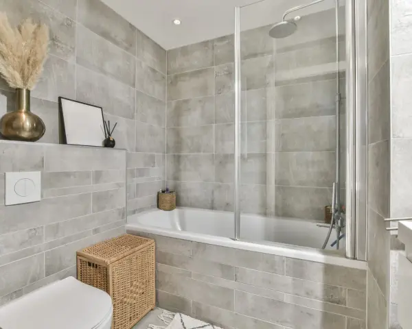 Salle de bain moderne avec carrelage gris. Une baignoire, une douche, un WC et un lavabo. Quelle colle pour carrelage salle de bain ? Une colle adaptée à l'humidité est essentielle.