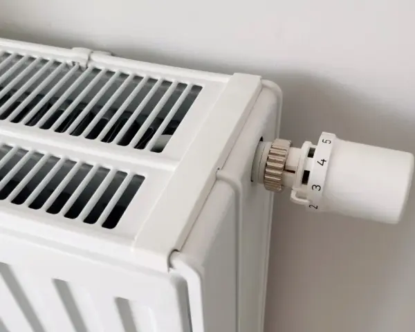 Biały grzejnik z termostatem. Dowiedz się, jak odpowietrzyć grzejnik, gdy przestaje efektywnie grzać.