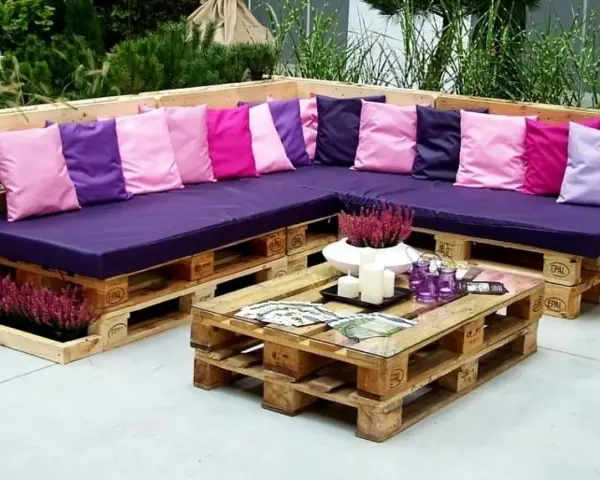 Narożna sofa i stolik kawowy z palet, ozdobione kolorowymi poduszkami i wrzosem. Prawdziwe cuda z palet!