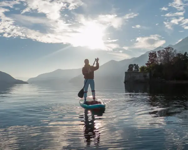 Person auf einem Stand Up Paddle Board, genießt die Aussicht und verbrennt dabei effektiv Stand Up Paddle Kalorien.