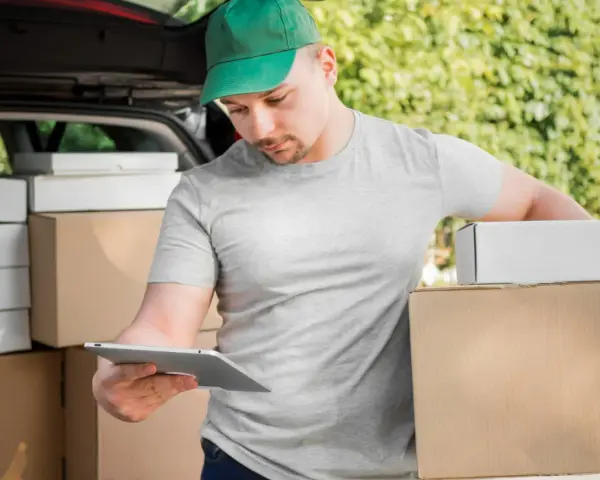 Kurier FedEx sprawdza paczki na tablecie. Zastanawiasz się, ile zarabia kurier FedEx?