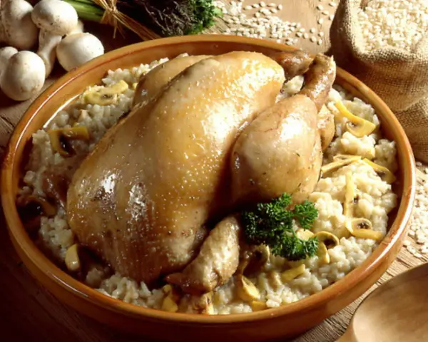 Un plat réconfortant de poule au riz crémeux, garni de champignons et d'une touche de persil frais.