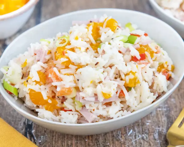 Omas Reissalat mit Orangenstücken, Schinkenwürfeln und Frühlingszwiebeln in einer Schüssel.