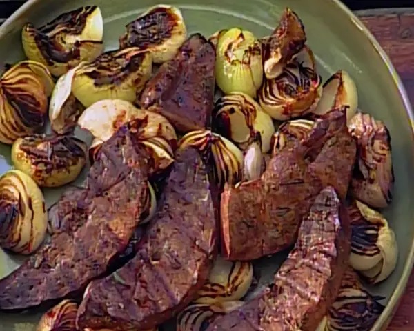 Sabroso hígado encebollado a la parrilla, con trozos de cebolla caramelizada y tiernas lonchas de hígado.