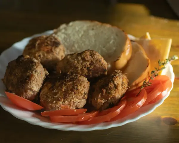 Talerz z kotletami mielonymi, kromkami chleba, pomidorami i serem. Idealny posiłek, jeśli zastanawiasz się, jaki kotlet mielony kcal.