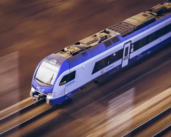 Pędzący pociąg TLK Flisak, którego rozkład jazdy jest kluczowy dla podróżnych, mija krajobraz w rozmytych barwach.