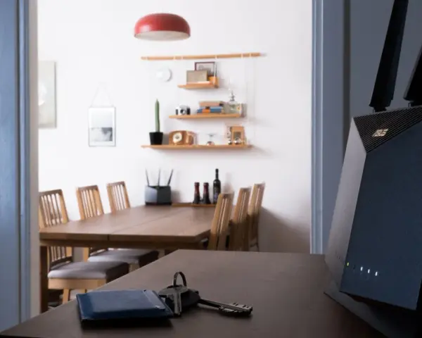 En modern router med wifi 4 ger snabb uppkoppling i hemmet. Nycklar och en blå korthållare ligger på bordet.
