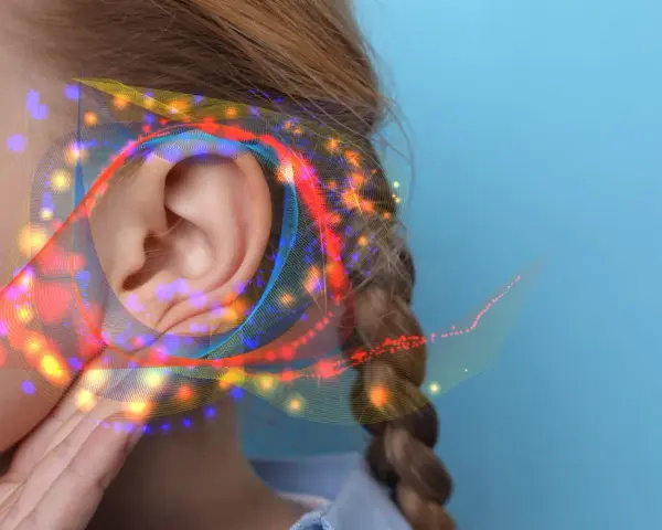 Une oreille capte des ondes sonores colorées, suggérant un seuil de douleur db.