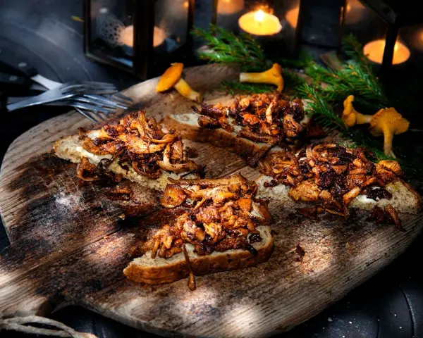 Smörstekta kantareller på bröd, ett enkelt och gott kantareller recept. Serveras på en träbricka med ljus och granris.