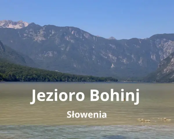 Spokojne jezioro Bohinj w Słowenii otoczone zielonymi wzgórzami i skalistymi górami.