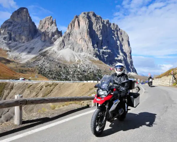 Motocyklista przemierza malowniczą drogę w Dolomitach. Pogoda dopisuje, a widoki zapierają dech w piersiach.